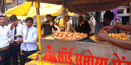 DISTRICT KATNI, INDIA - SEPTEMBER 24, 2019: an indian having fresh vada samosa together at street food carriage shop in market street.のeditorial素材