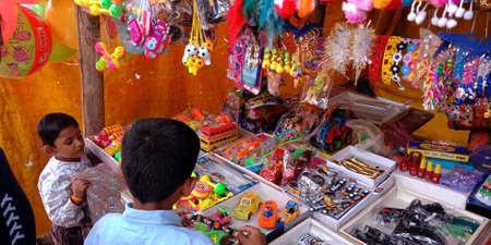 DISTRICT KATNI, INDIA - OCTOBER 13, 2019: An indian little boy buying toys at hindu temple street store in village area.のeditorial素材
