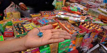 DISTRICT KATNI, INDIA - OCTOBER 15, 2019: Colorful Crackers presented on hand by asian vender for selling during hindu tradition Diwali festival at indian street city bazaar.のeditorial素材