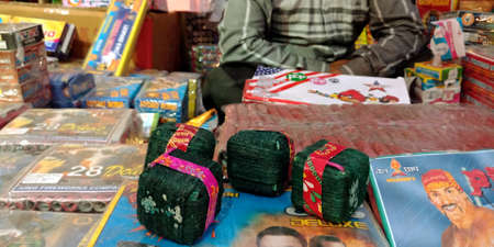 DISTRICT KATNI, INDIA - OCTOBER 15, 2019: Green color item bomb Crackers displayed by asian salesman for selling during hindu tradition Diwali festival at indian street city bazaar.のeditorial素材