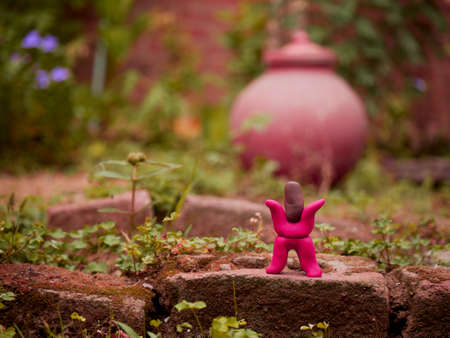 Red color cartoon man standing upon bricks around garden made with clay artの写真素材