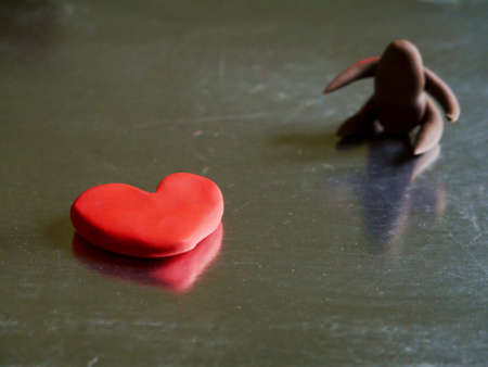 Red color heart shape clay with blur cartoon men on side frame presented for loving conceptの写真素材