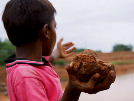 Indian village boy throwing stone on river, Stone closeup on hand kids lifestyle concept.の写真素材