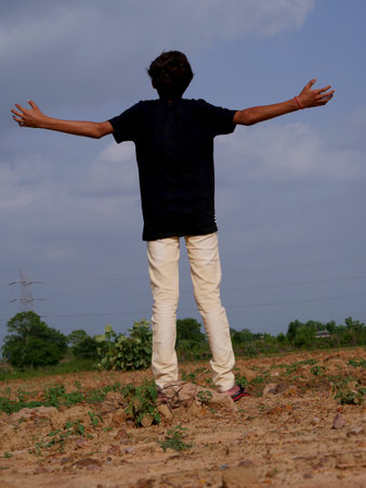 Indian boy back pose with spreading hand on sky background, lifestyle concept.の写真素材