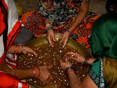Three traditional women making Jaggery dry fruit sweet for festival in india.の写真素材