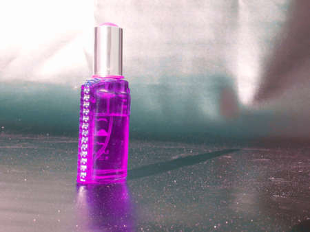 Purple perfume bottle kept on dark surface with shadow reflection.