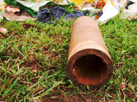 paper object lying on green grass soil field with garbage stock on background.の写真素材