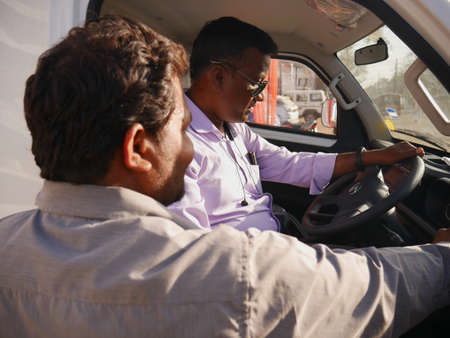 DISTRICT KATNI, INDIA - MARCH 02, 2022: An indian male customer testing truck feature while sitting on driving seat, other man is explaining feature from outside of vehicle.のeditorial素材