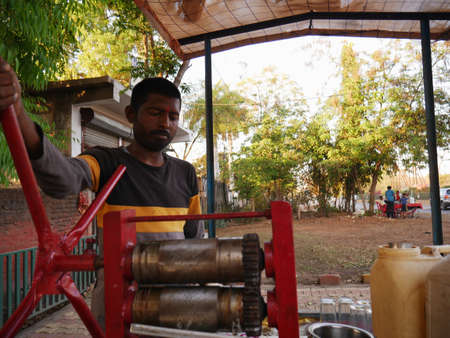 DISTRICT KATNI, INDIA - MARCH 02, 2022: An indian street vendor making sugarcane juice from hand...