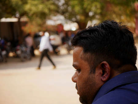 An indian man looking at right side, face closeup around blur people background at day time at city Katni Madhya Pradesh in India on March 2022.のeditorial素材