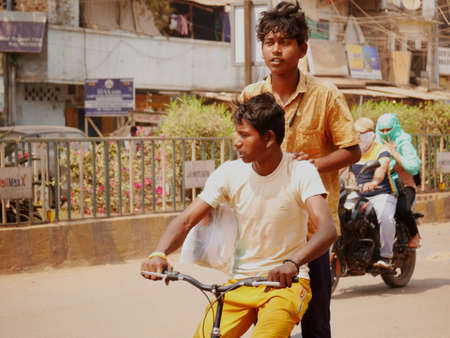 Two indian boys riding bicycle with funny style on road during traffic at city Katni Madhya Pradesh in India on March 2022.のeditorial素材