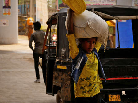An indian unidentified village poor girl coming with sack on head during transportation at city...