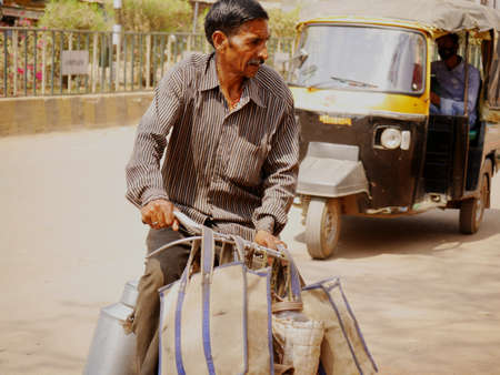 unidentified indian poor man riding cycle with heavy luggage carrying on hand during city traffic at city Katni Madhya Pradesh in India on March 2022.のeditorial素材