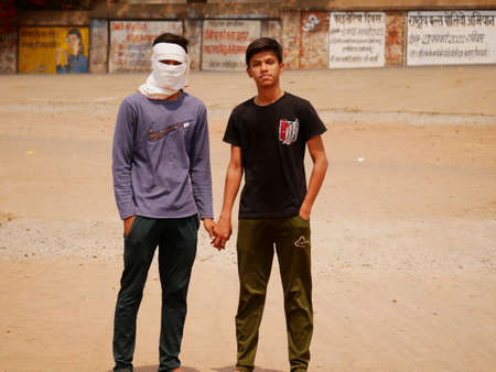 Two boys standing together while one is covered face from cloths due to covid impact and sun light protection at city Katni Madhya Pradesh in India on March 2022.のeditorial素材