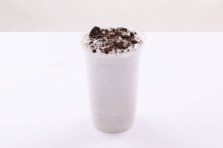 vanilla milkshake with black biscuit crumbs topping white background isolatedの写真素材