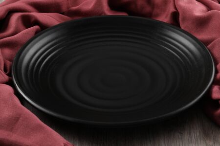 black plate with red napkin on wood backgroundの写真素材