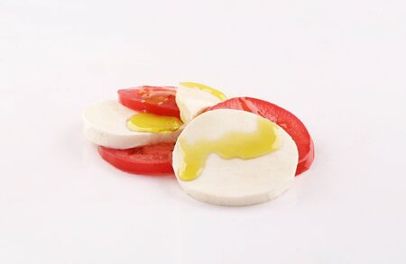 traditional italian salad contains mozzarella cheese, tomato, olives oil and oregano on white...
