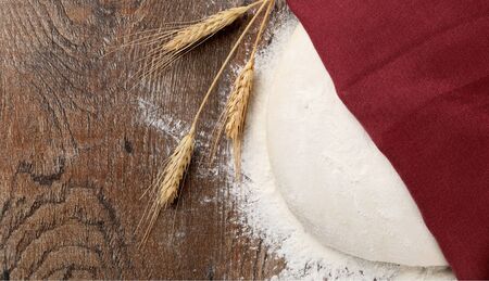 dough under napkin with Wheat ears and Sprinkles of flour on wood background top viewの写真素材