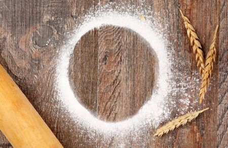 Wheat ears and Sprinkles of flour, rolling pin on wood backgroundの写真素材