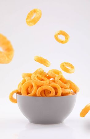 puffed corn rings chips in gray bowl and sprinkled isolated on white backgroundの写真素材