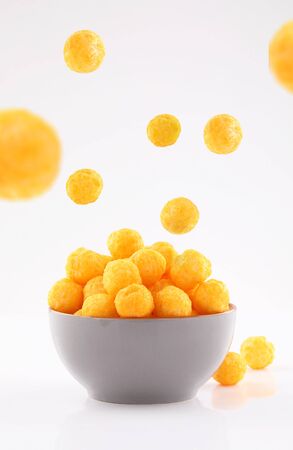 puffed ball cheese corn chips in gray bowl and sprinkled isolated on white backgroundの写真素材