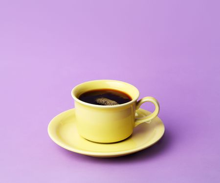 A yellow cup of fresh coffee on a lilac colored backgroundの写真素材
