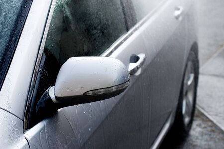 A Car being washed by a waterspray from a hose.