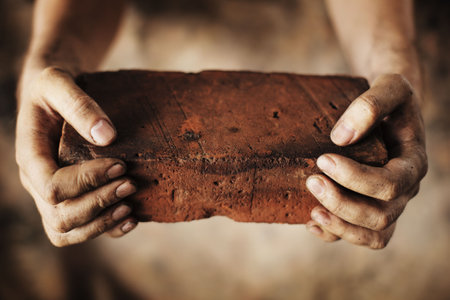 Dirty hands holding an old brickの写真素材