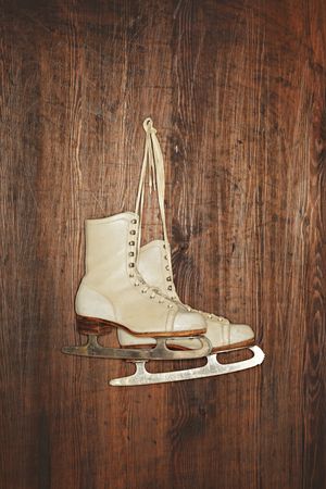 A Pair of old women's old skates hanging on a wooden wall. Photographed with a ring flash.の写真素材
