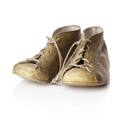 A Pair of old baby shoes on white reflecting backgroundの写真素材