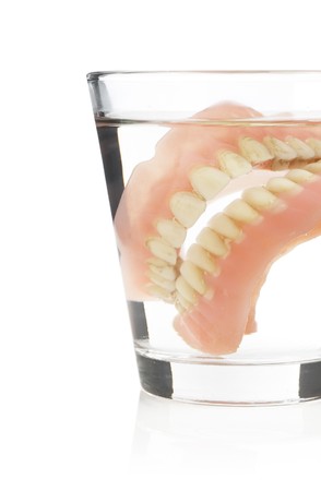 Old dentures in a glass of waterの写真素材