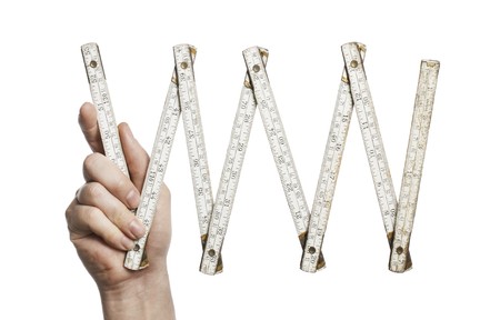 Man holding an old folding carpenter's ruler in his hand.の写真素材