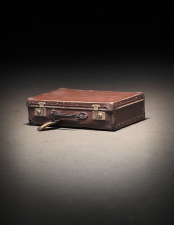 Old worn brown suitcase on dirty concrete floorの写真素材