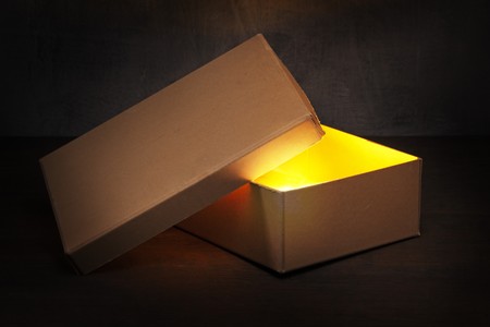 An Old brown cardboard box with glowing contents.の写真素材