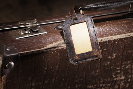 Old luggage tag on an old brown suitcase.の写真素材