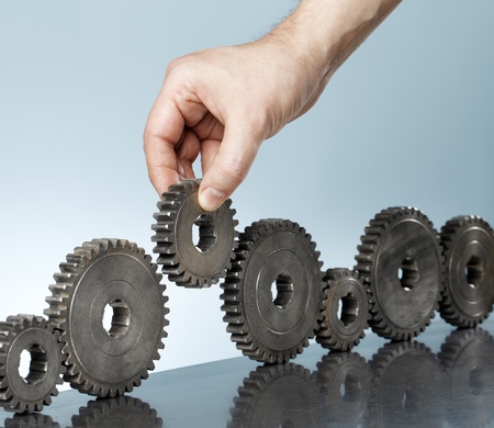 Man adding a cog gear in a row of old cog gears.の写真素材