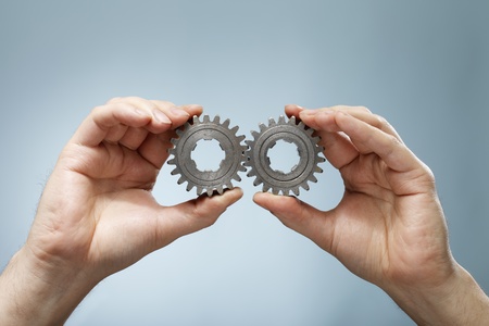 A Man holding a matching pair of old cog gear wheels in his hands.