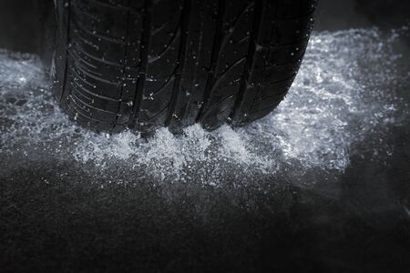 A Car tire on a wet road. The rain groove is a design element of the tread pattern specifically arranged to channel water away from the footprint.の写真素材