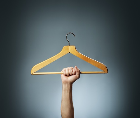 Man holding an old wooden hanger in his hand.の写真素材