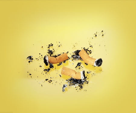 Burnt cigarette butts on yellow background.の写真素材