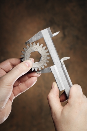 Man measuring the diameter of old cog with vernier caliper.の写真素材