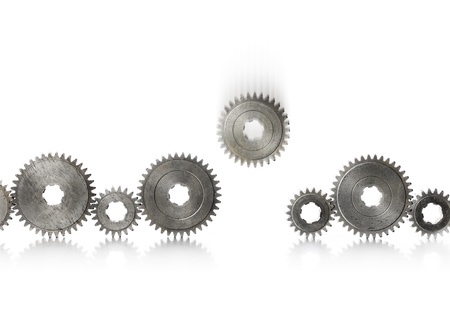 A row of old metallic cog gears being filled with one blurry falling gear.の写真素材