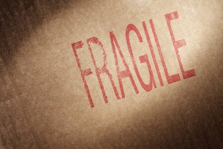 Closeup of a brown cardboard box with word "Fragile" stamped with red ink.の写真素材