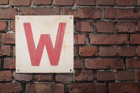 Old sign with letter W on a brick wall.の写真素材