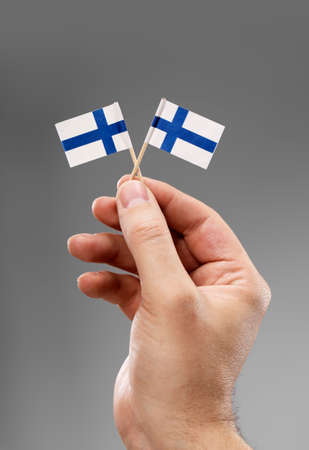 Man holding two small flags of Finland in his hand.の写真素材