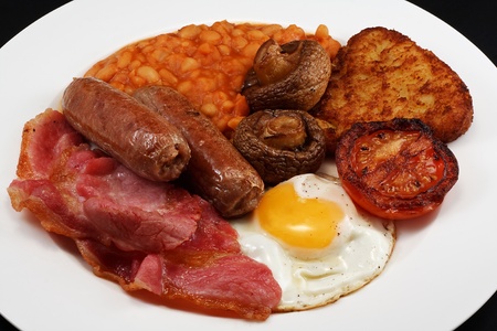Typical full breakfast consisting of Sausage, bacon, egg, mushrooms, hash browns, beans and Fried Tomatoの写真素材