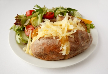 A Cheddar cheese baked potato on a plate with side saladの写真素材