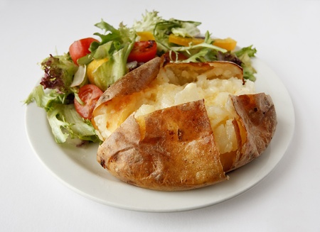 A plain butter baked potato on a plate with side saladの写真素材