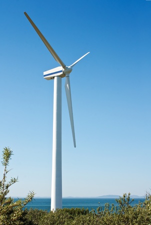 a single coastal on shore wind turbine used to generate electricity at wind farms, on a clear sky with text areaのeditorial素材