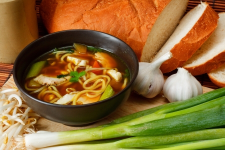 chicken noodle soup a popular and favorite variety worldwide surrounded by ingredients and crusty breadの写真素材